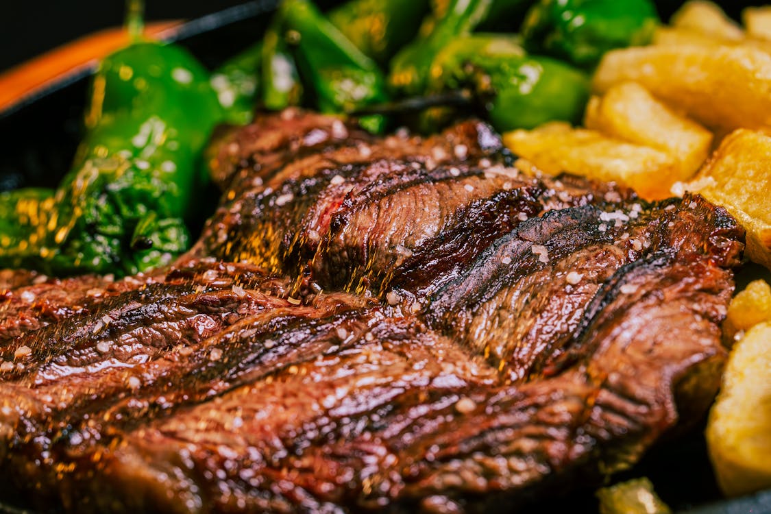 Free Juicy grilled beef steak served with green peppers and crispy fries. Stock Photo