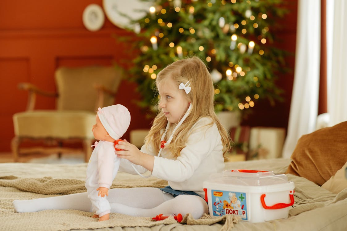 Free A Young Girl Sitting on the Bed While Playing Stock Photo