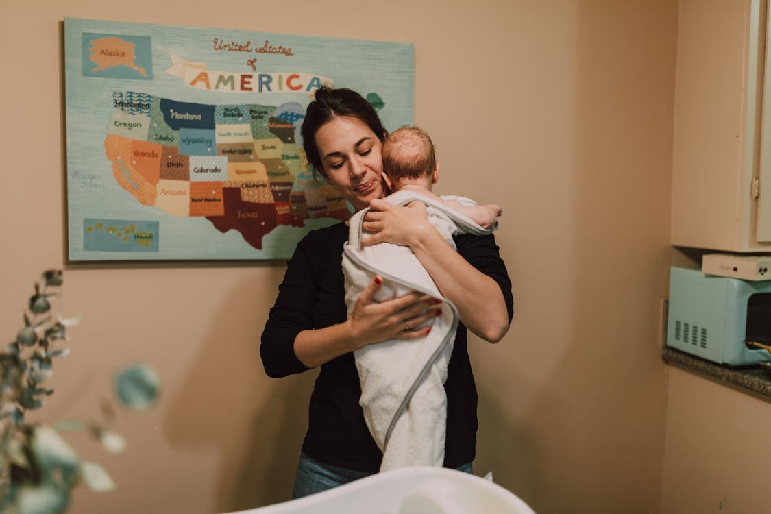 Free A caring mother holds her newborn baby in a warm indoor setting. Stock Photo