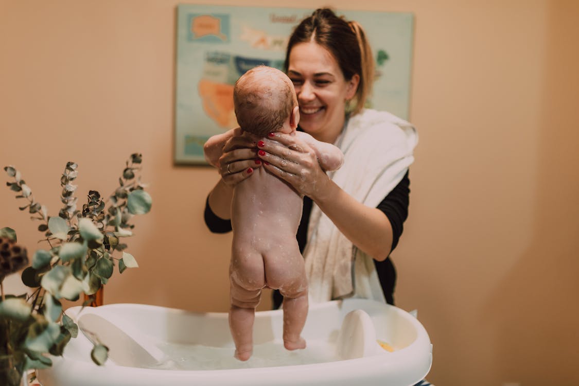 Free A joyful mom giving her baby a bath, showcasing intimate family moments at home. Stock Photo