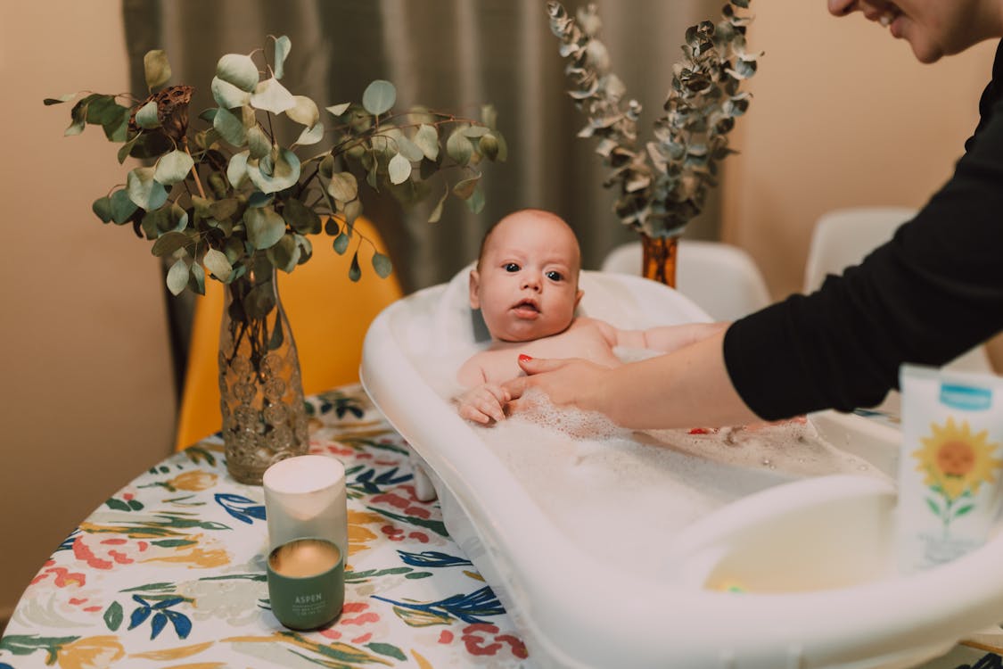 Free A heartwarming scene of a baby enjoying a bubble bath with parental care and soothing ambiance. Stock Photo