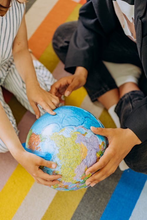 Free Two Kids Holding and Studying A Globe Stock Photo