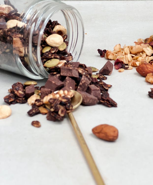 Free Close-up of a spilled jar of homemade granola mix with chocolate and nuts. Stock Photo