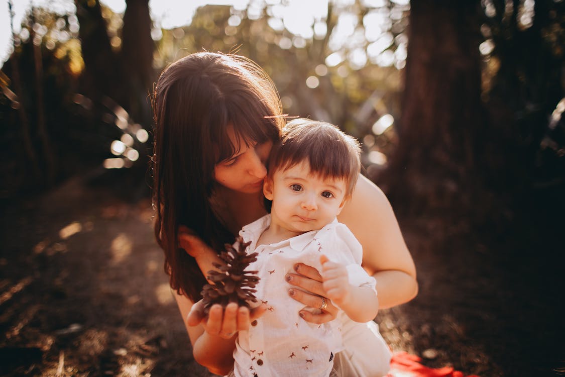 Free Mother Holding Baby Son in Forest Stock Photo