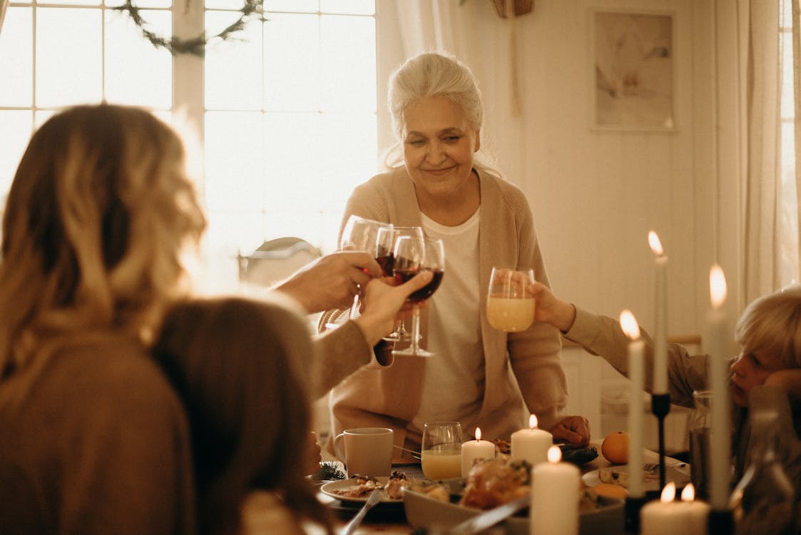 Free A joyful family dinner where people toast with various drinks surrounded by candlelight. Stock Photo