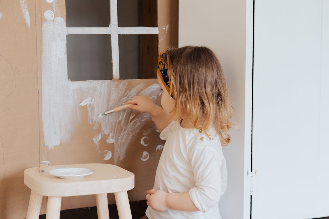 Free Girl in White Shirt Painting on Cardboard Play House Stock Photo