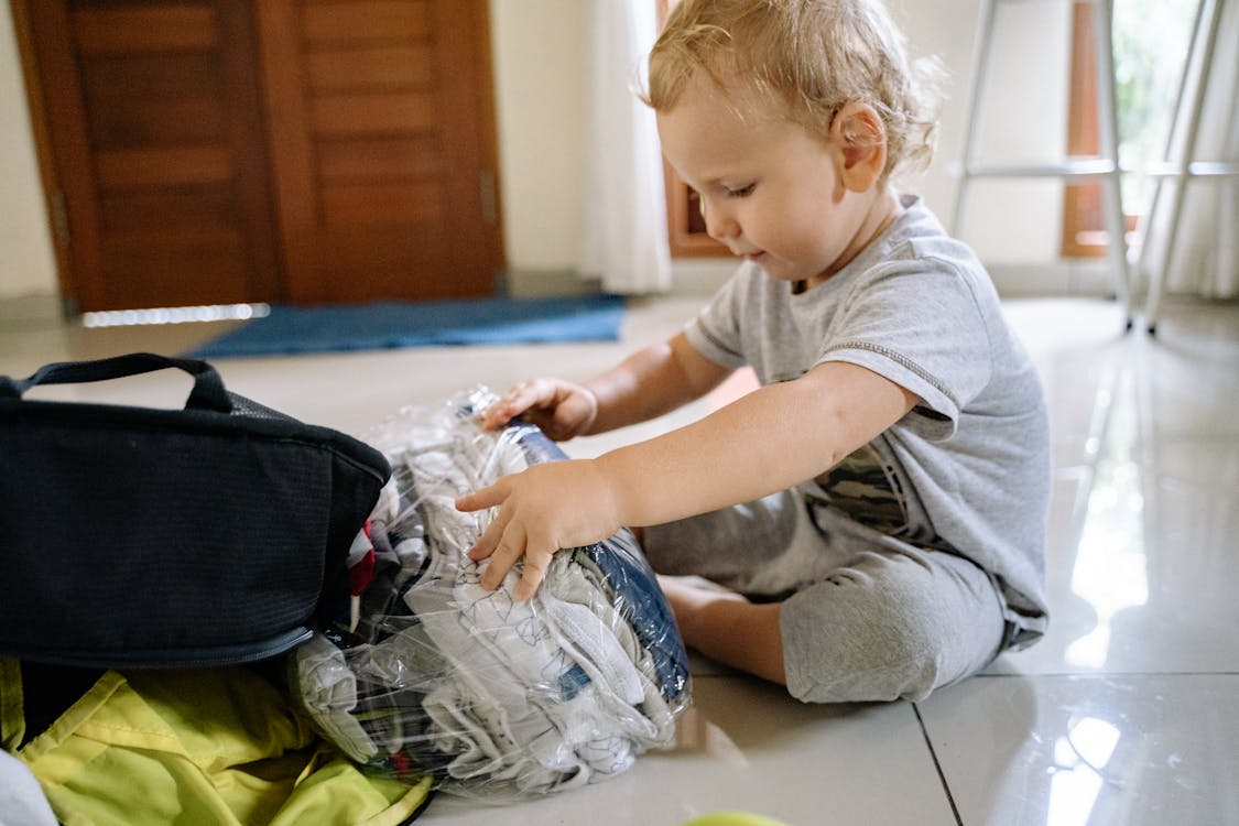 Free Boy in Gray Crew Neck T-shirt and Gray Pants Sitting on White Floor Tiles Stock Photo