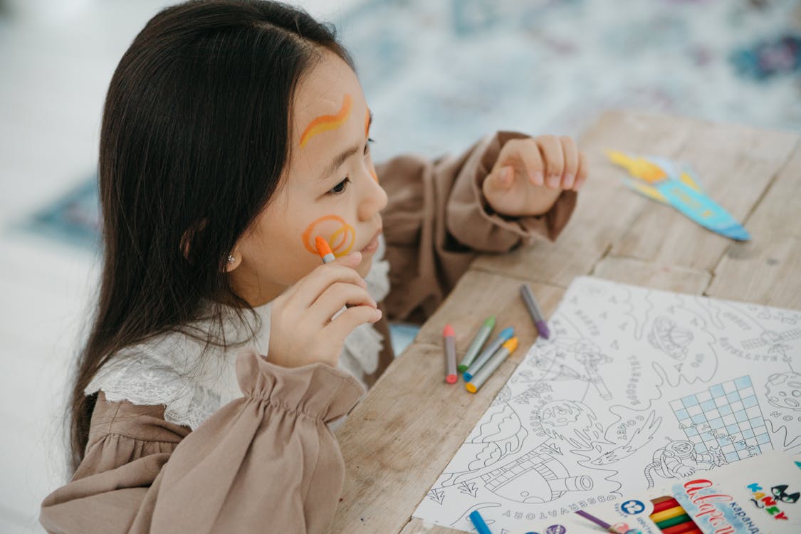 Free Young girl having fun with face painting and drawing, expressing creativity and joy. Stock Photo