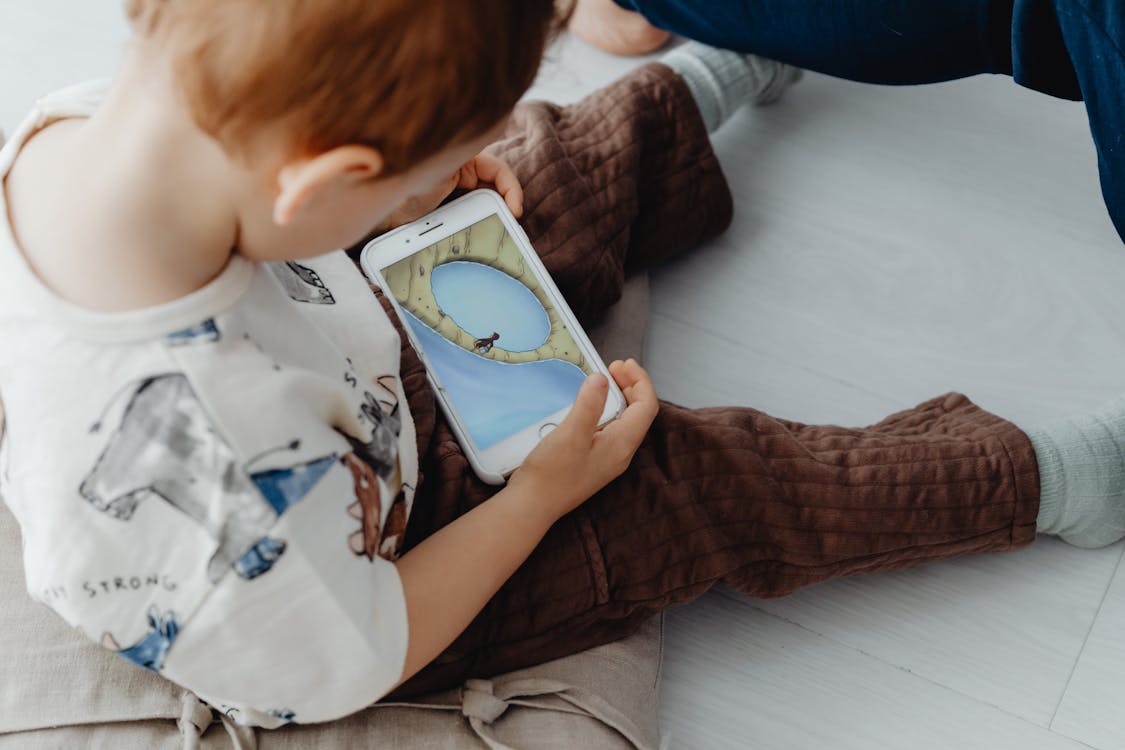 Free Little Child Playing Game on Mobile Phone Stock Photo