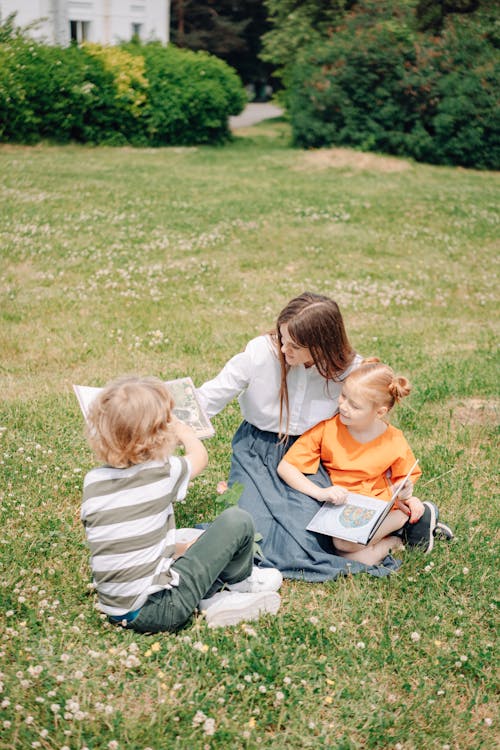 Free A Woman Sitting at the Park while Talking to the Kids Stock Photo