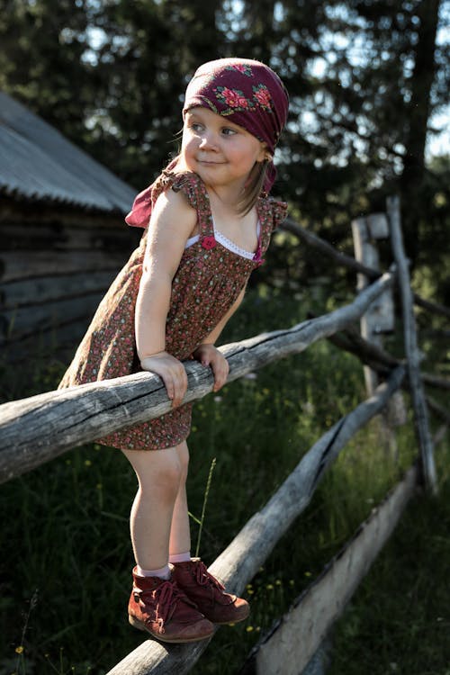 Free A Young Girl Climbing on Wooden Fence Stock Photo