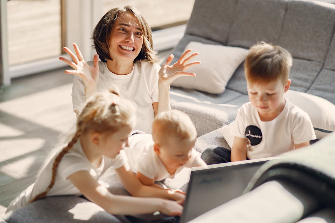 Free A mother looking stressed while her children play on a laptop in a living room. Stock Photo