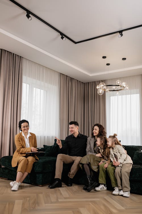 Free Family discusses new home purchase with real estate agent in a cozy living room setting. Stock Photo